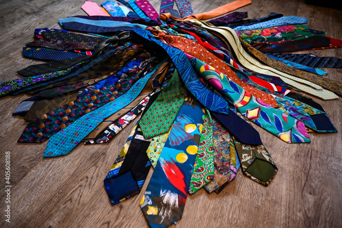 A bundle of colorful  oldfashioned business ties is lieing on a wooden floor.