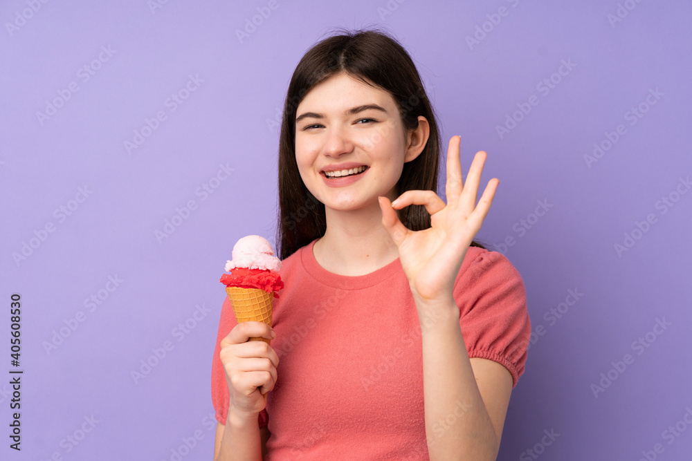 Young Ukrainian teenager girl holding a cornet ice cream over isolated purple background showing ok sign with fingers Young Ukrainian teenager girl holding a cornet ice cream over isolated purple background showing ok sign with fingers