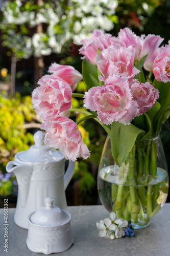 Vase with light pink tulip flowers in spring sunny garden
