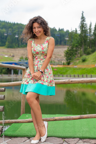A beautiful slim girl posing in green summer park next to pond © Kate
