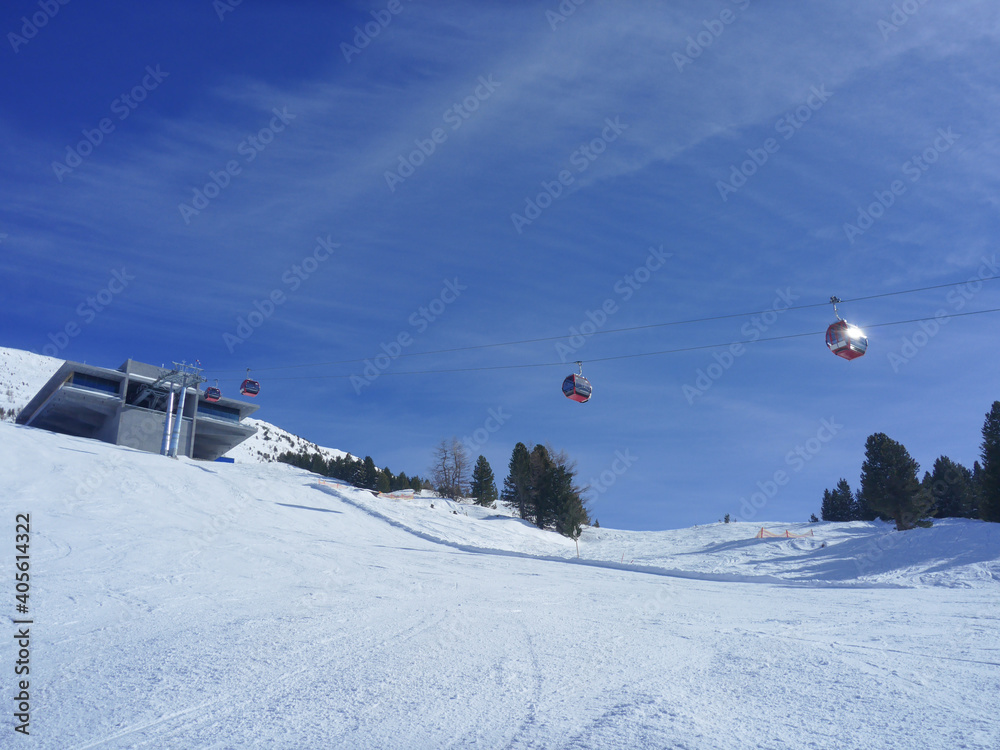 Leere Skipiste mit roten Gondel und Bergstation in Tirol
