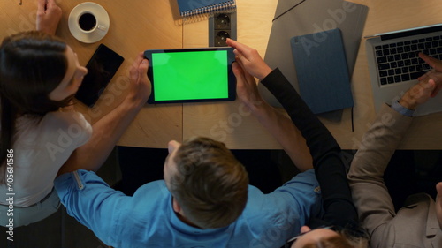 Team working together in coworking. Man showing tablet green screen colleagues.