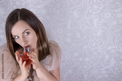 A fairy tail concept of an attractive woman in a glittery retro style party Christmas or wedding dress holding a glass of rose wine looking happy