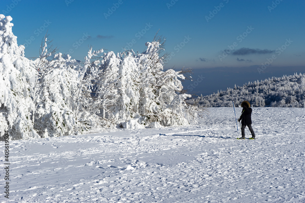 Man with snowshoes at Markstein ski resort on a cold sunny day.