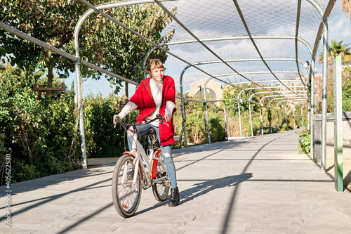 Caucasian young girl in red jacket riding on a bike ride in the park