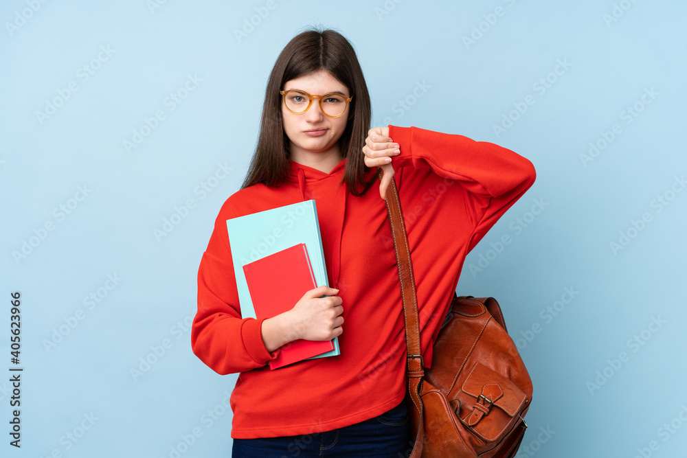 Obraz premium Young Ukrainian teenager student girl holding a salad over isolated blue background showing thumb down sign