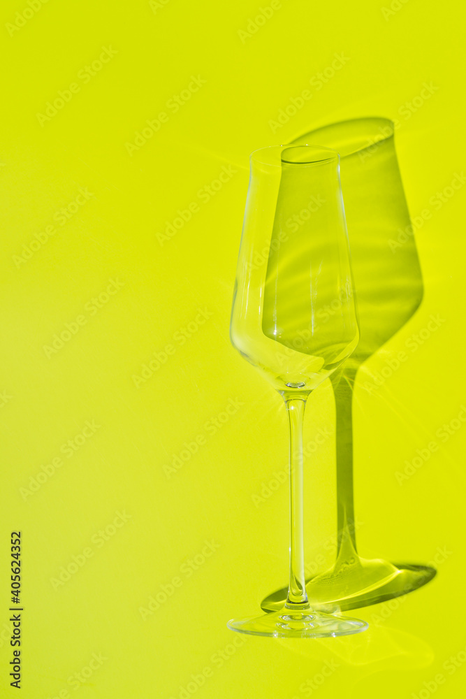 Champagne glass lies on lemon green surface. Glass with hard shadow Champagne glass lies on lemon green surface. Glass with hard shadow