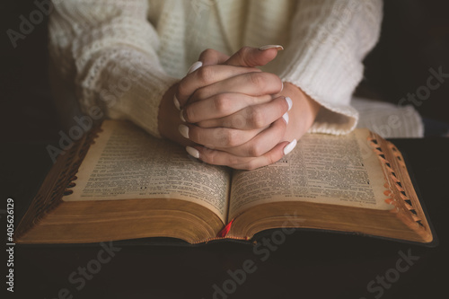 Obraz na płótnie Girl with her hands clasped on top of an open vintage Bible