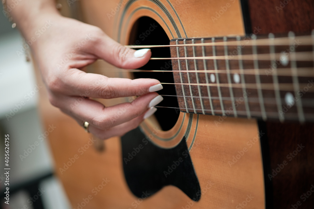 girl's hands playing an acoustic guitar