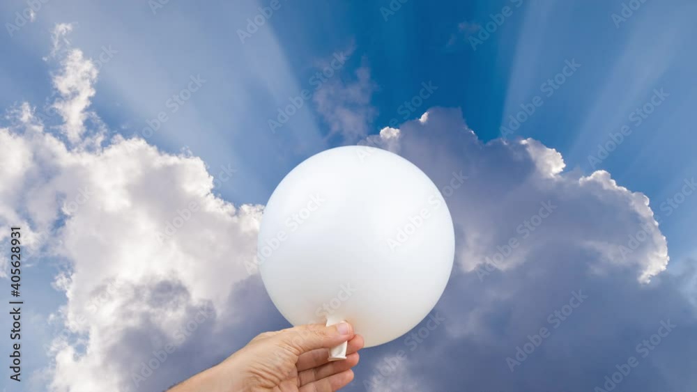 White balloon being blown up against a sky with clouds