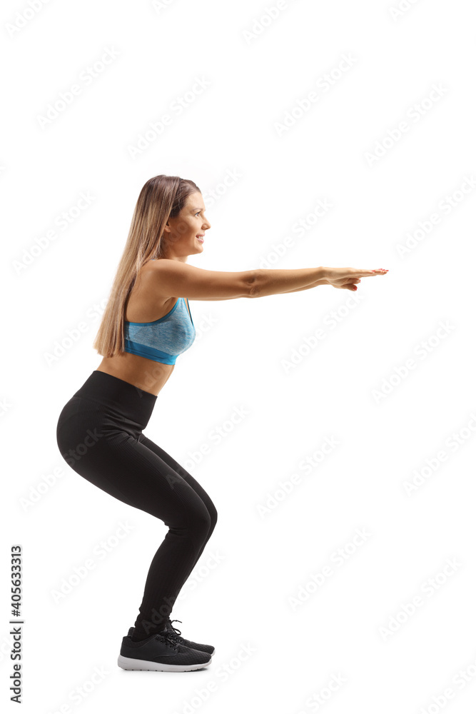 Full length profile shot of a young woman in sportswear exercising squats Full length profile shot of a young woman in sportswear exercising squats