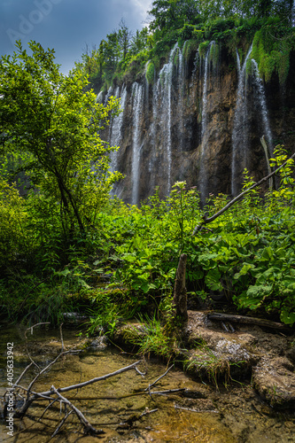 Beautiful waterfall illuminated by sunlight with little pond in green lush forest  Plitvice Lakes National Park UNESCO World Heritage in Croatia