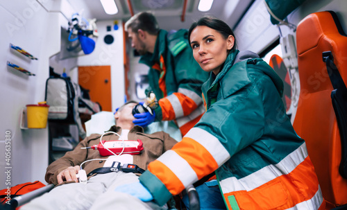 Doctors emergency or paramedics are working with a senior man patient while he lies on a stretcher in an ambulance. photo