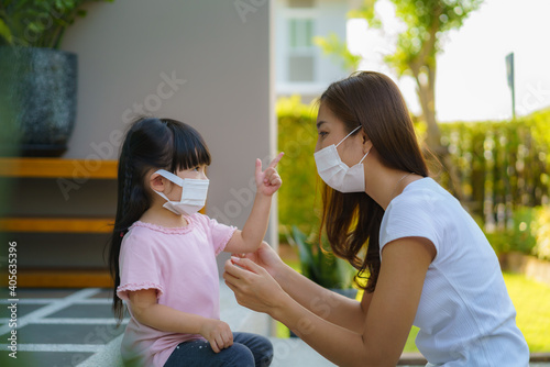 Asian mother help her daughter wearing protection mask to protect the coronavirus Covid-19 outbreak situation before go to school. Get ready to school concept..
