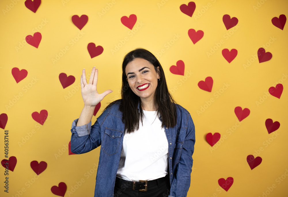 Young caucasian woman over yellow background with red hearts doing star trek freak symbol Young caucasian woman over yellow background with red hearts doing star trek freak symbol