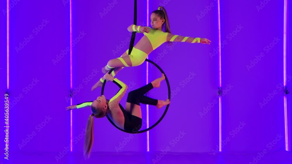 Two young circus performers rotate on an air hoop. Girls in yellow and ...