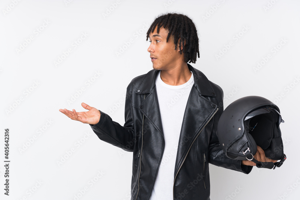 Young african american man holding a motorcycle helmet isolated on white background with surprise facial expression Young african american man holding a motorcycle helmet isolated on white background with surprise facial expression