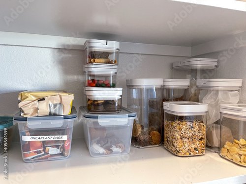 An organized pantry shelf with various types of cookies, cereal and snacks photo