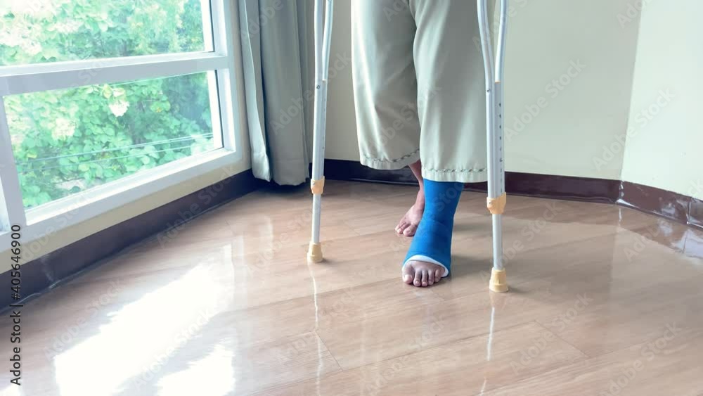 A male patient in splint walking with crutches in hospital, step forward walk with crutches for injured leg or leg splint. healthcare concept A male patient in splint walking with crutches in hospital, step forward walk with crutches for injured leg or leg splint. healthcare concept