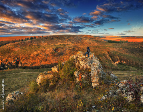 Woman on a hiking trip in the mountains walking on rocks. colorful autumn sunrise