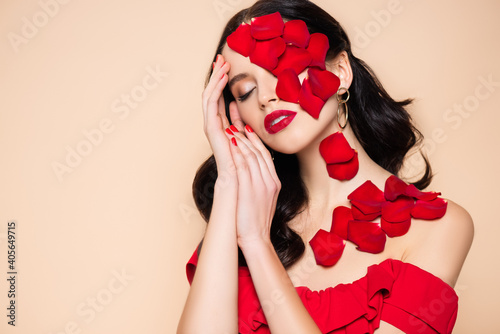 pretty young woman with closed eyes and rose petals on face isolated on pink