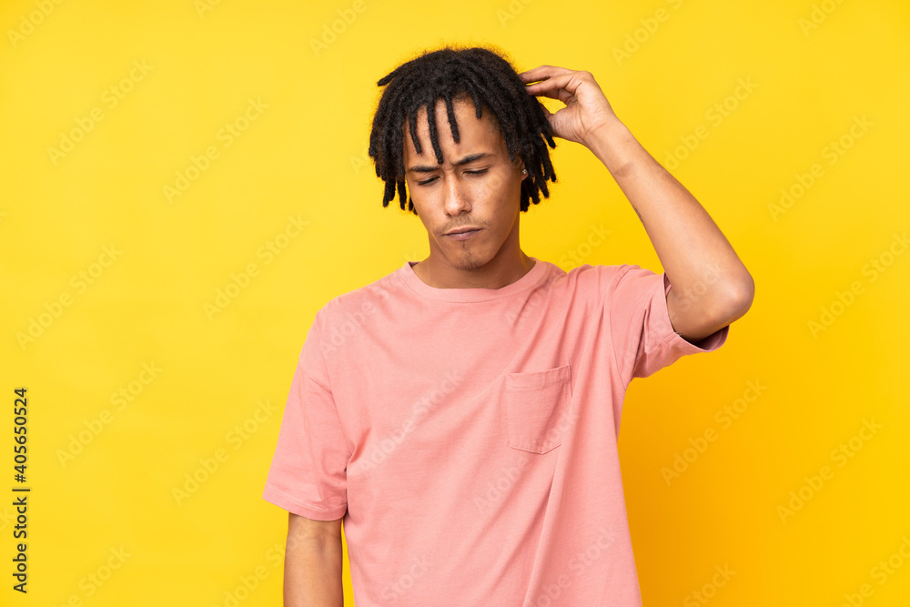 Young african american man isolated on yellow background having doubts while scratching head Young african american man isolated on yellow background having doubts while scratching head