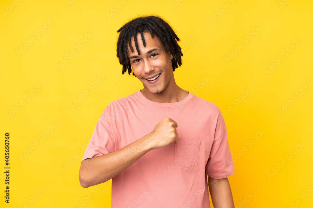 Young african american man isolated on yellow background celebrating a victory