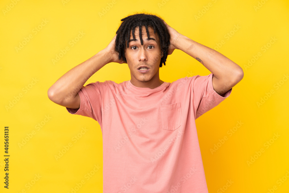 Young african american man isolated on yellow background frustrated and takes hands on head Young african american man isolated on yellow background frustrated and takes hands on head