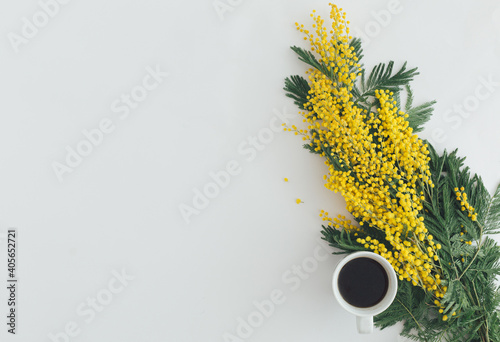 Coffe with yellow mimosa flower on white background. Minimal flat lay photo