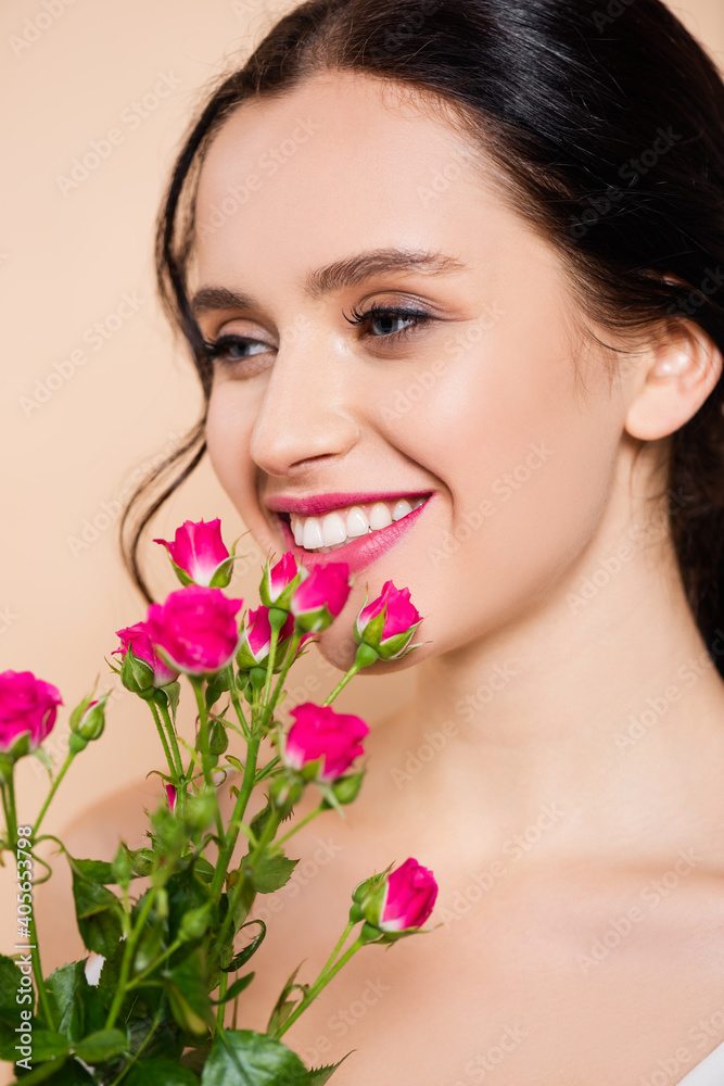 cheerful young woman smiling near flowers isolated on pink cheerful young woman smiling near flowers isolated on pink
