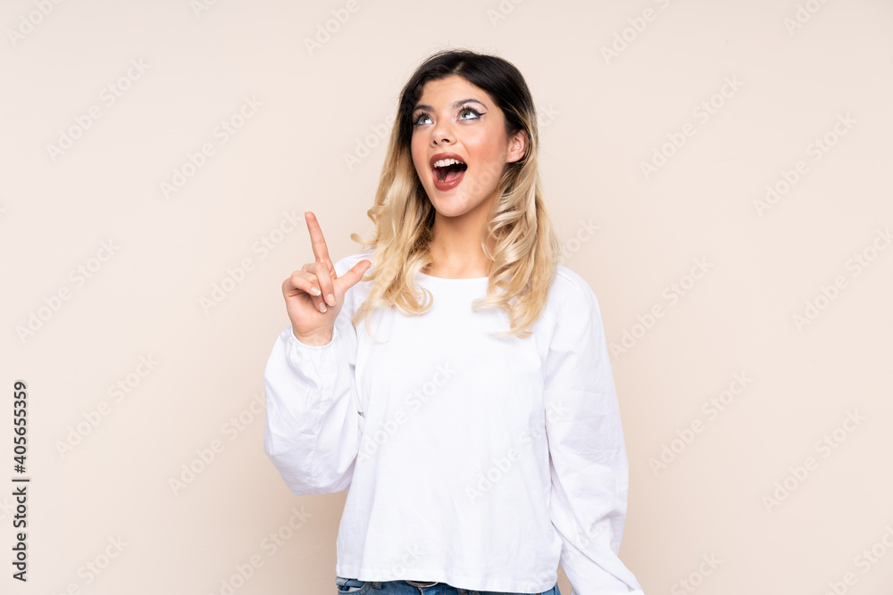 Teenager girl isolated on beige background pointing up and surprised Teenager girl isolated on beige background pointing up and surprised