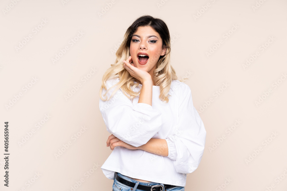 Teenager girl isolated on beige background surprised and shocked while looking right Teenager girl isolated on beige background surprised and shocked while looking right