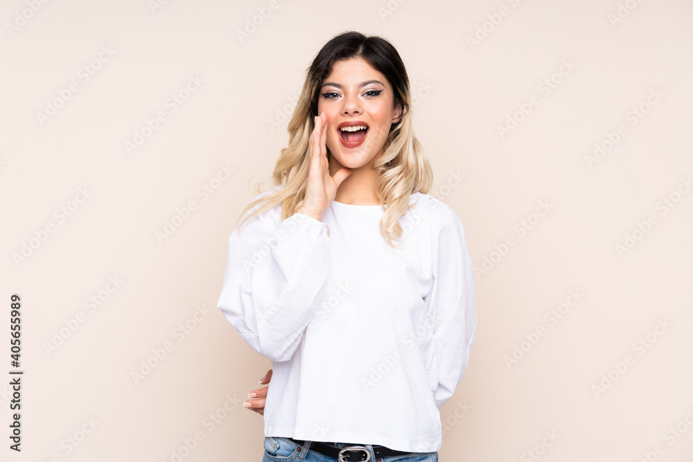Teenager girl isolated on beige background shouting with mouth wide open Teenager girl isolated on beige background shouting with mouth wide open
