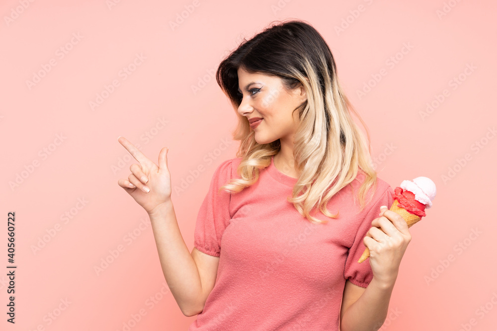 Teenager girl holding a cornet ice cream isolated on pink background pointing to the side to present a product Teenager girl holding a cornet ice cream isolated on pink background pointing to the side to present a product
