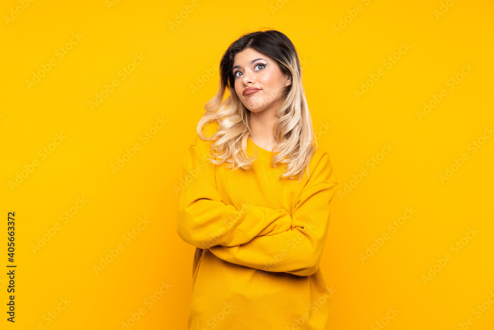 Teenager girl isolated on yellow background making doubts gesture while lifting the shoulders Teenager girl isolated on yellow background making doubts gesture while lifting the shoulders
