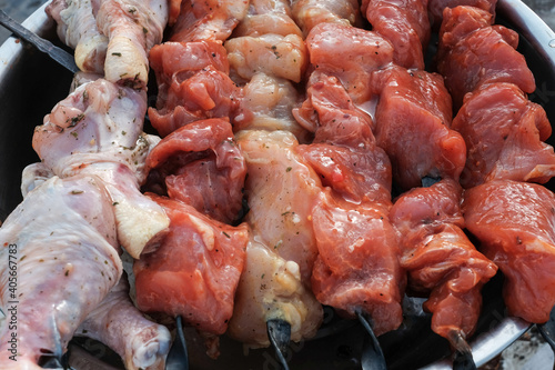 Raw pork skewers and chicken thighs cut into pieces and on skewers closeup