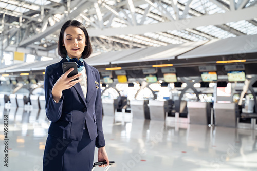 Canvas-taulu Caucasian beautiful flight attendant using mobile phone in the airport