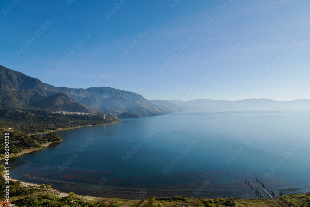 Lake Atitlan in Guatemala in the morning seen from the viewpoint in San Juan la Laguna - landscape of lake surrounded by mountains with sunrise light
