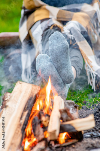 Woman warming feet in socks near a bonfire
