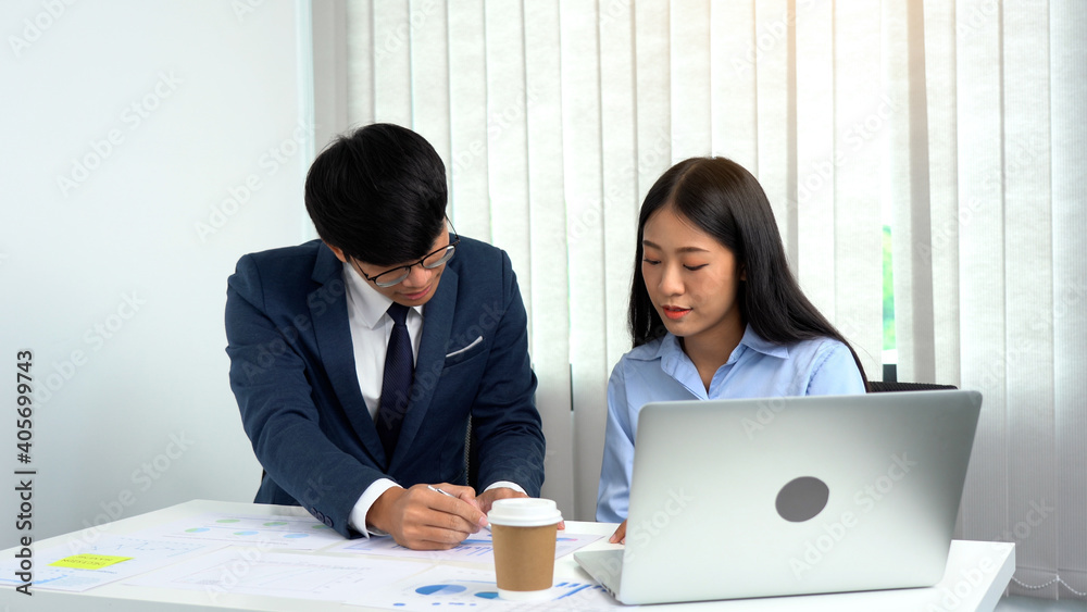 Asian male manager teaches the staff about bookkeeping at their desks. Asian male manager teaches the staff about bookkeeping at their desks.