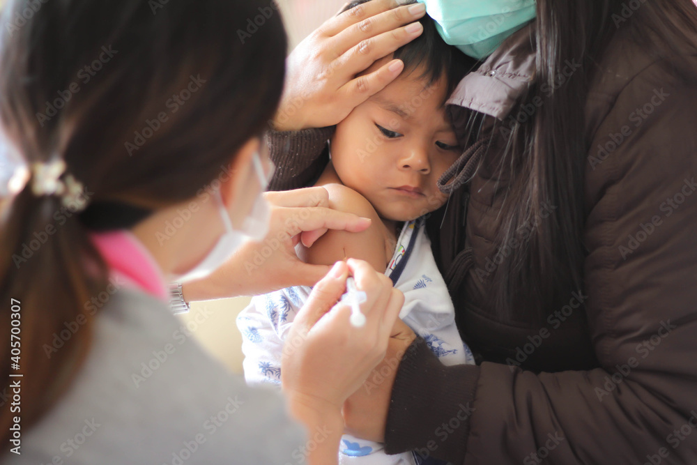 Vaccination concept. Female doctor vaccinating a cute little boy With her mother carried in the clinic Vaccination concept. Female doctor vaccinating a cute little boy With her mother carried in the clinic