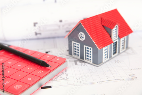 Small house model, calculator and a pencil on the housing decoration drawings