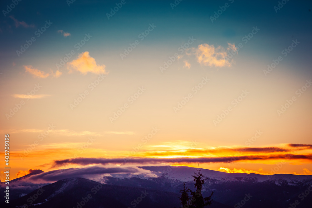 Beautiful dawn in the winter snow-covered mountains and amazingly beautiful clouds