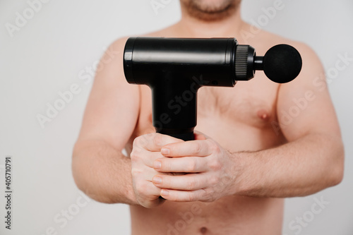 focus on the subject. man holds massage gun. medical-sports device helps to reduce muscle pain after training, helps to relieve fatigue, affects problem areas of body, improves condition of skin.