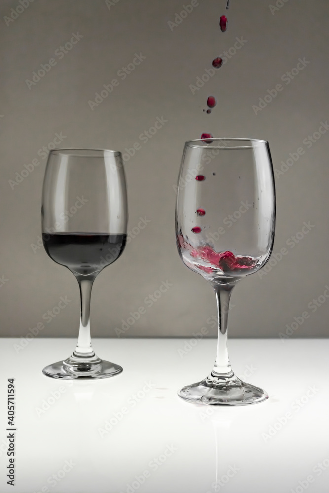 Fototapeta premium Red wine is poured from a bottle into a glass on a blurred background, close-up.