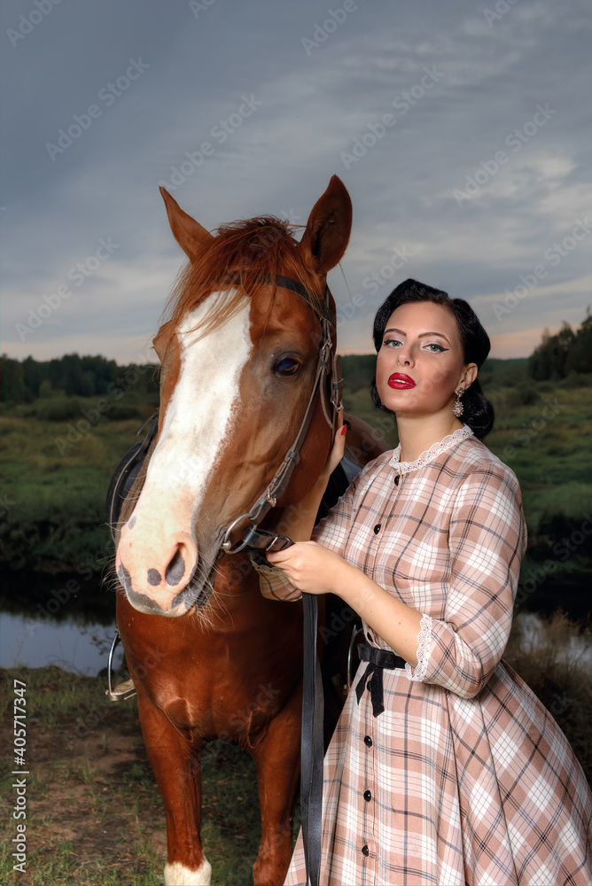 Fototapeta premium Young beautiful woman in a retro dress next to a horse.