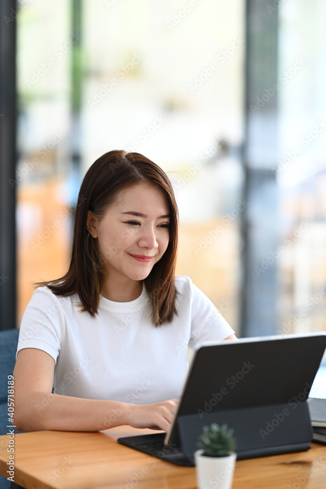 Portrait of happy young female freelance working on tablet computer while sitting at comfortable workplace. Portrait of happy young female freelance working on tablet computer while sitting at comfortable workplace.