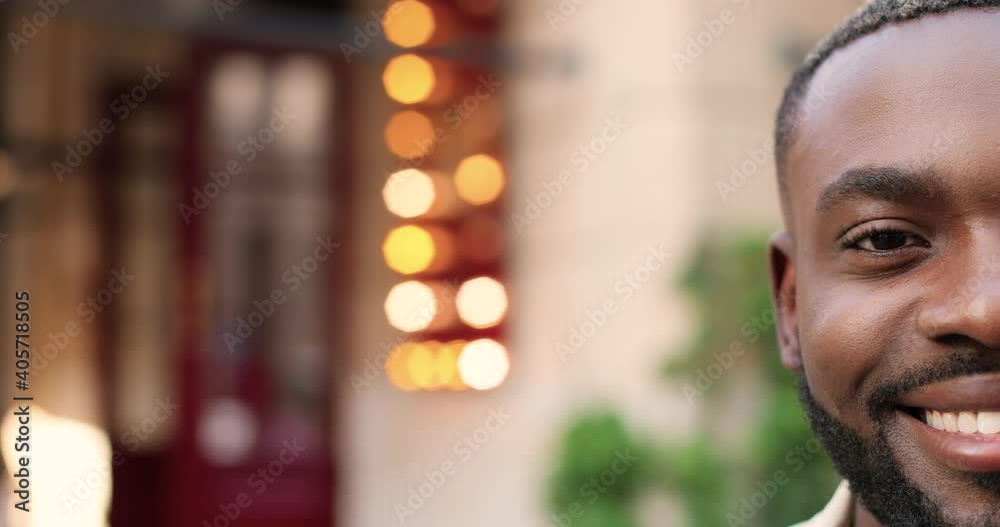 Close up of half face of young African American handsome man with beard looking at camera and smiling joyfully. Portrait of good-looking happy guy with smile outdoor. Close up of half face of young African American handsome man with beard looking at camera and smiling joyfully. Portrait of good-looking happy guy with smile outdoor.
