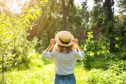 Hipster girl in straw hat standing in the forest. Wanderlust concept. Travelling ideas. Beautiful woman in the nature. Summer vibes. © Vadym