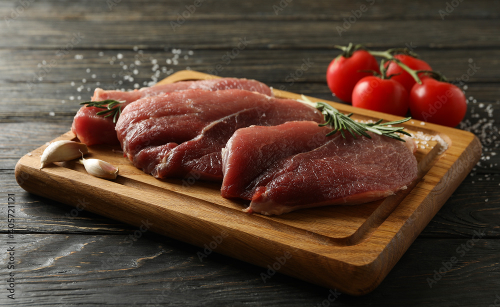 Board with fresh raw steak meat on wooden background